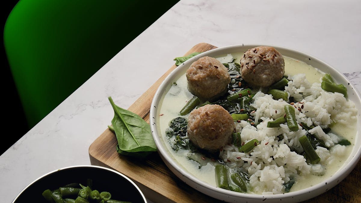 A savory dish of meatballs, rice, and green beans on a decorative plate.